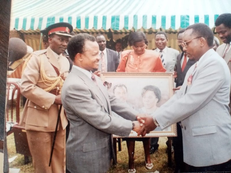 Former Zambian President H.E. Fredrick Chiluba shakes hands with Leonard Kateete after receiving his portrait (in the background) in the late 1980s.